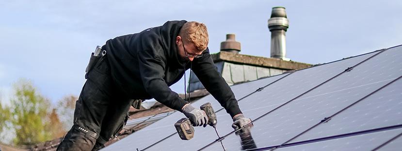 Ein Installion-Mitarbeiter montiert eine Photovoltaik-Anlage auf einem Dach