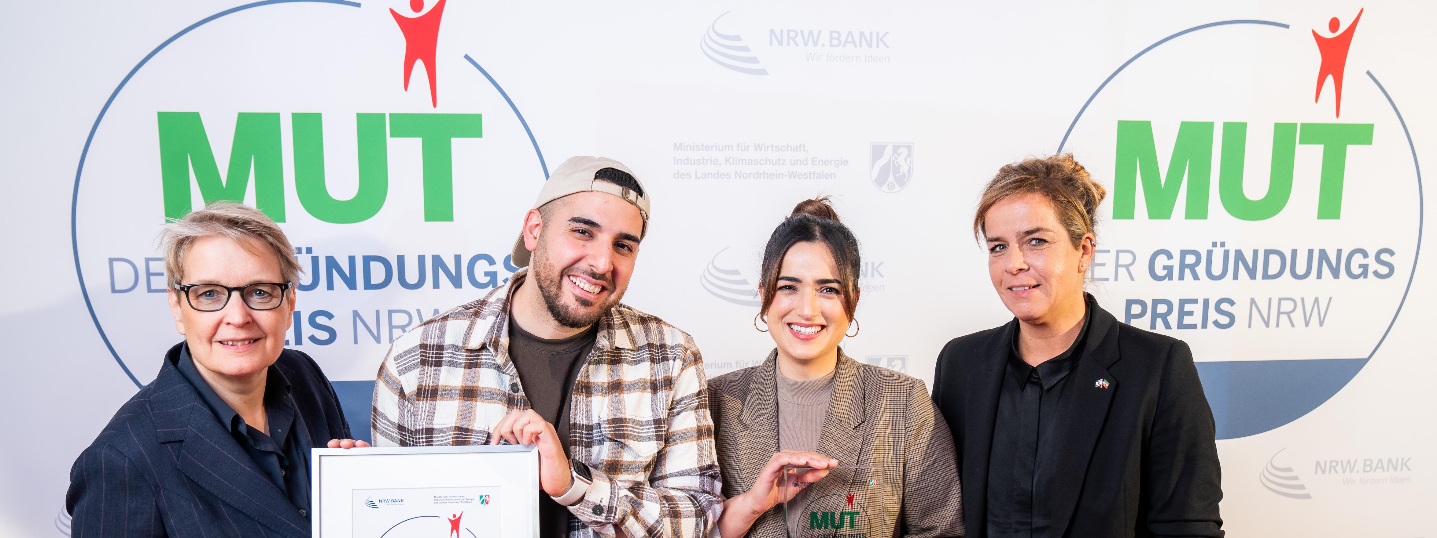 Die Gewinner des dritten Preises mit Ministerin Mona Neubaur vor der Logowand