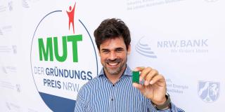 Martin Riebe, Gründer von Incoretex vor dem Logo vom Gründungspreis NRW