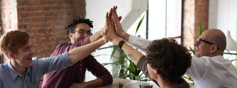 Vier Menschen geben sich ein High-Five