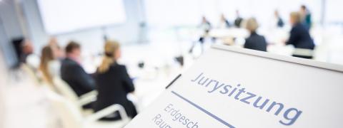 A sign indicates a jury meeting, in the background people around a table
